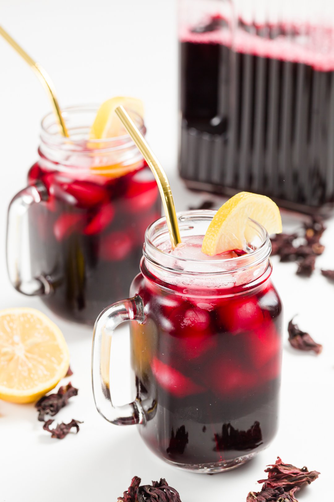 Two glasses of iced hibiscus tea garnished with lemon