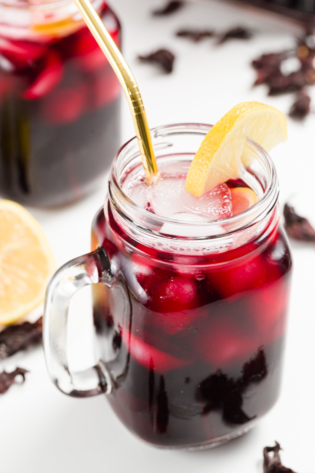 A glass of iced hibiscus tea garnished with lemon