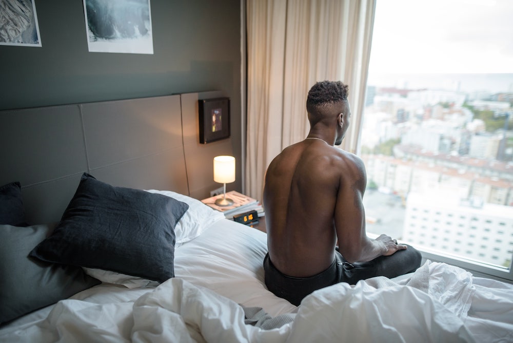 black man sitting in bed in the morning