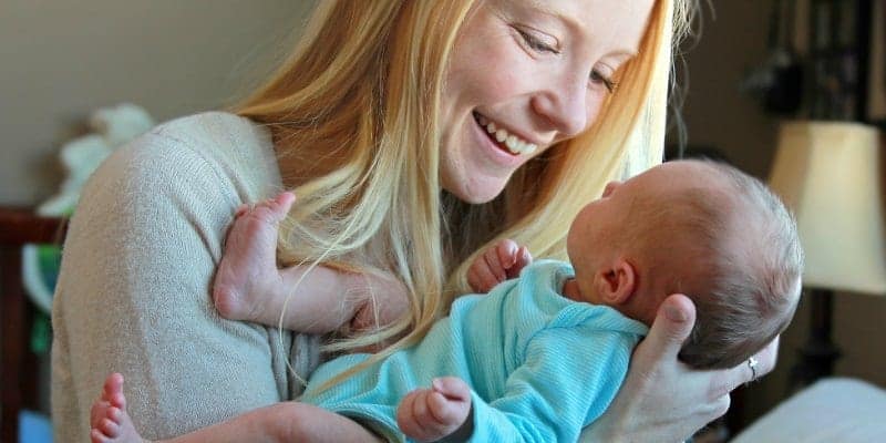 mom holding newborn baby and smiling