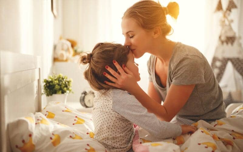 a stay at home mom kissing daughter