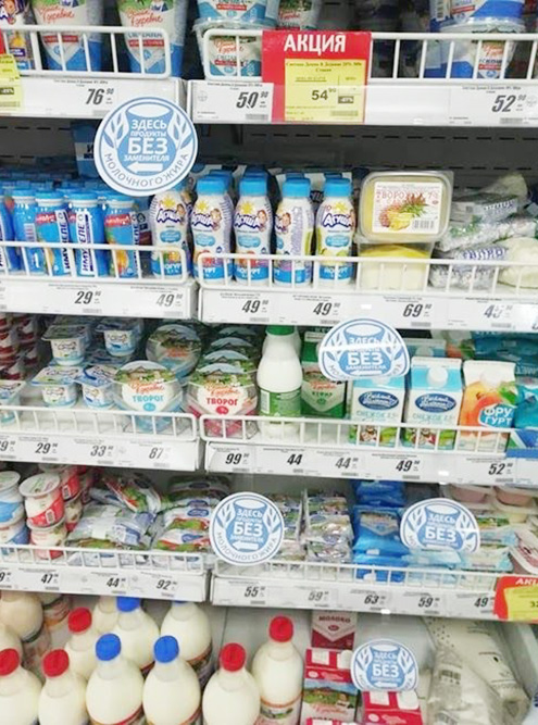 Продукты, в которых молочный жир заменен растительным, на полках магазинов отделены специальными значками или разделителями. СЗМЖ означает «с заменителем молочного жира»