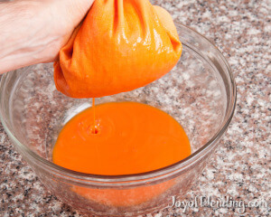 Straining carrot juice with nut milk bag