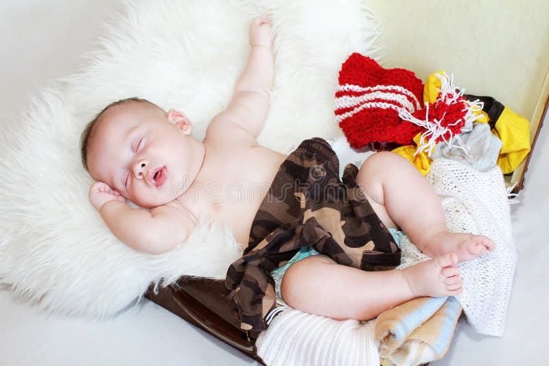 Baby sleeping in suitcase with clothes royalty free stock photography