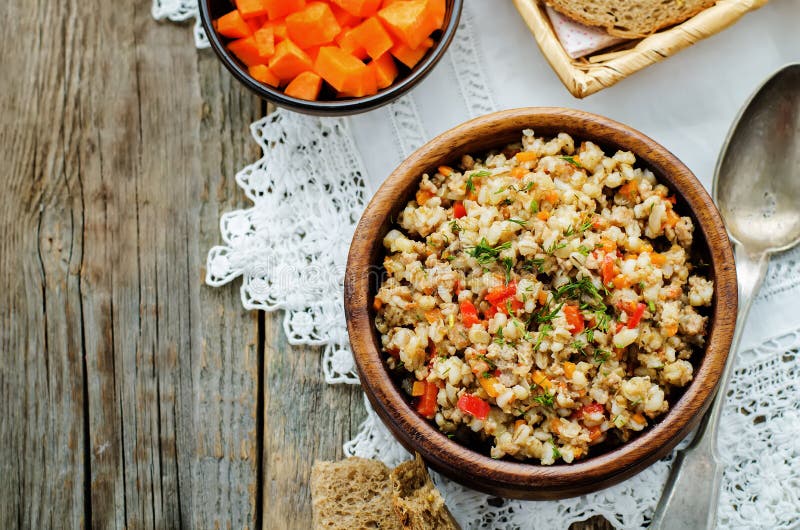 Barley porridge with meat and vegetables. On a dark wood background. tinting. selective focus royalty free stock photography