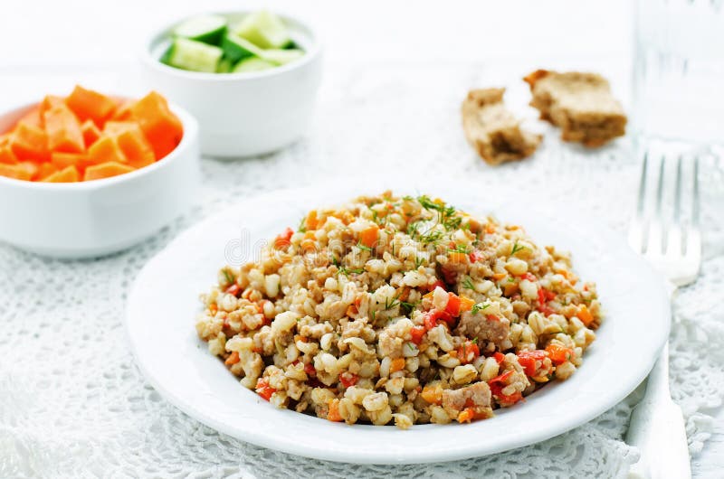 Barley porridge with meat and vegetables. On a white background. tinting. selective focus stock photography