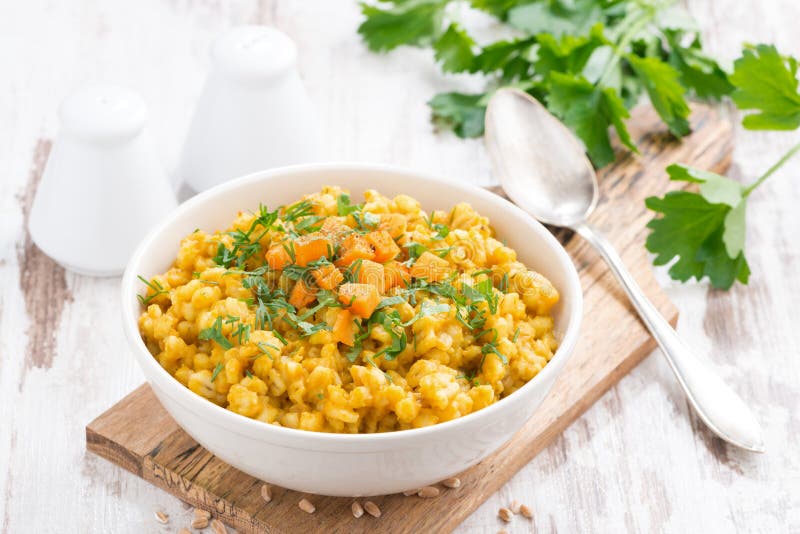 Barley porridge with pumpkin and greens in a bowl, horizontal. Top view stock photography