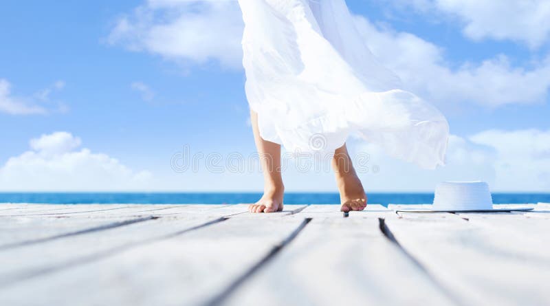 Beautiful and healthy woman’s legs in white skirt on a wooden. Pier. Vacation, resort and traveling concept stock photo