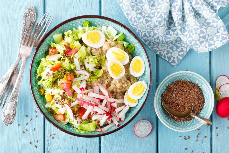 Bowl with wheat porridge, boiled quail eggs and fresh vegetable salad of radish, corn, sweet pepper and chinese cabbage. Healthy a royalty free stock photos