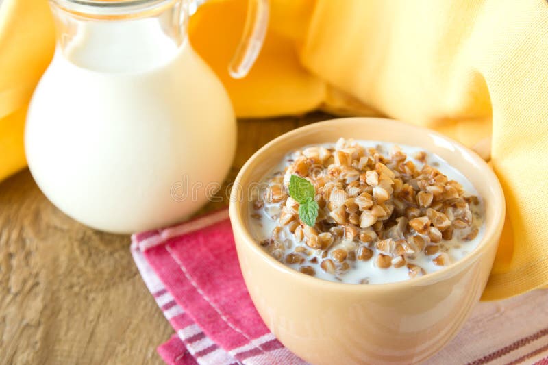 Buckwheat with milk. Buckwheat porridge with milk and mint on wooden table, close up, horizontal. Natural organic vegetarian food (breakfast royalty free stock photo