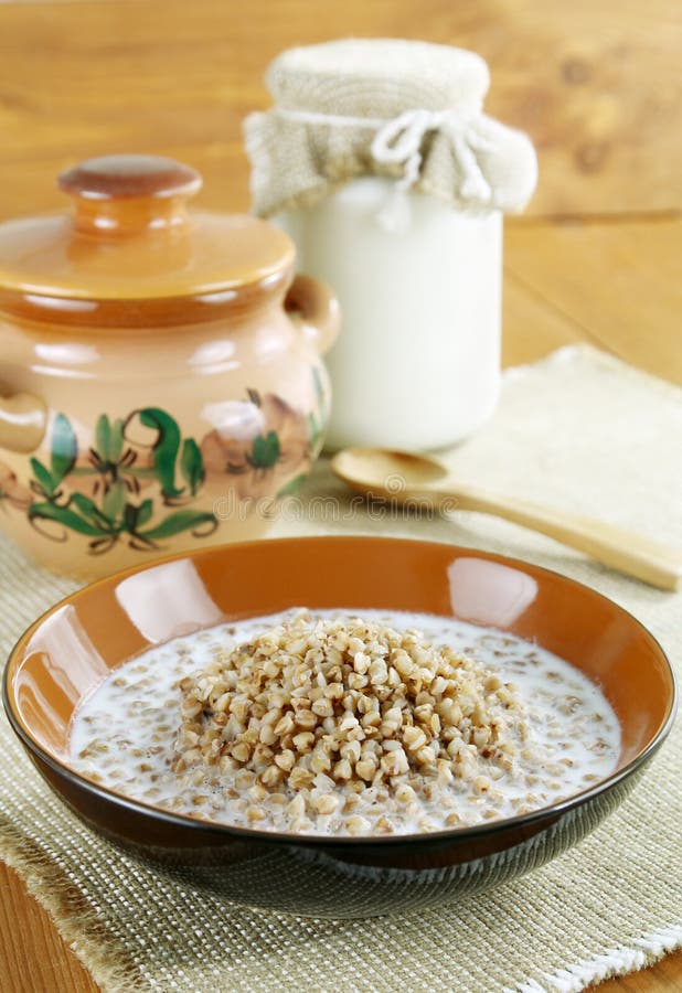 Buckwheat porridge with milk. A bowl of buckwheat porridge and milk on a wooden table stock photos