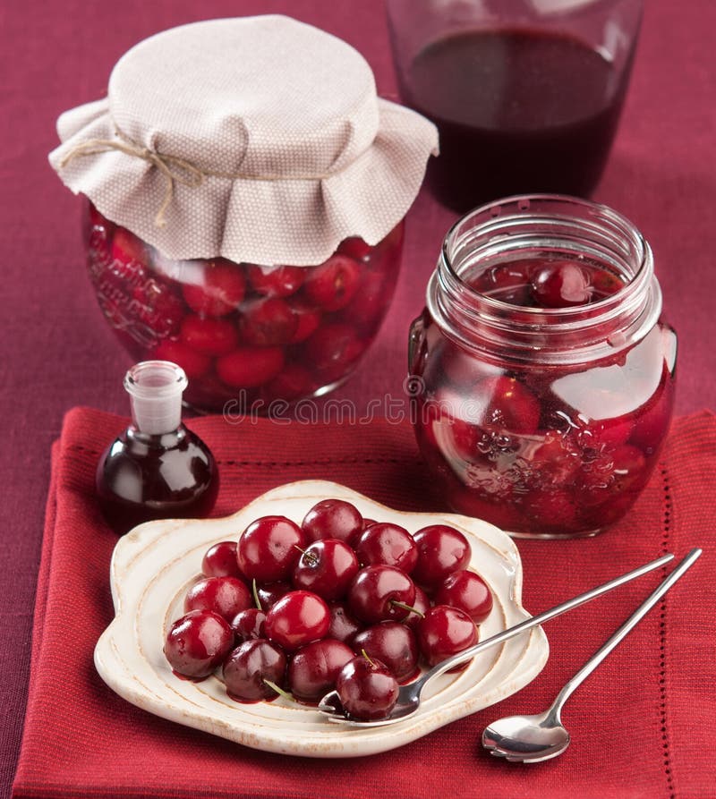 Cherry in juice in the pot. On a red napkin royalty free stock photography