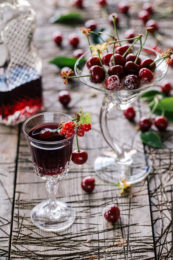 Cherry tincture. In a glass and bottle on the background of a rustic table stock photos