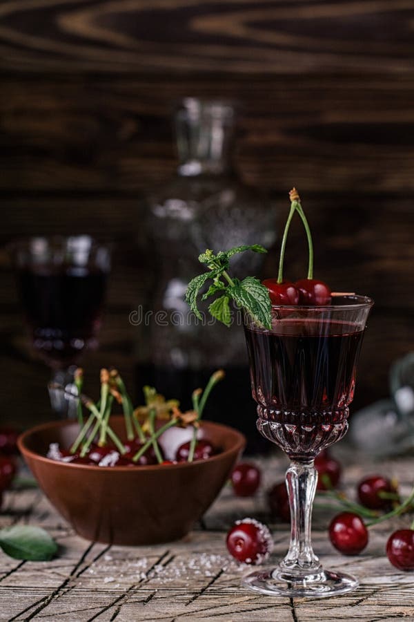 Cherry tincture. In a glass and bottle on the rustic background royalty free stock photography
