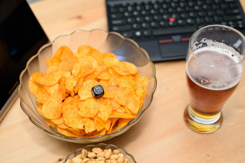 Closeup of unhealthy snack and beer with laptop in background. Stock photo stock photography