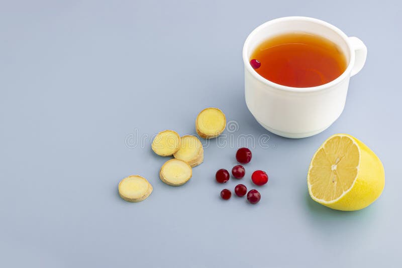 Cup of tea, ginger, lemon and cranberry as folk remedies on blue background  with copy space for text. The concept of seasonal royalty free stock image
