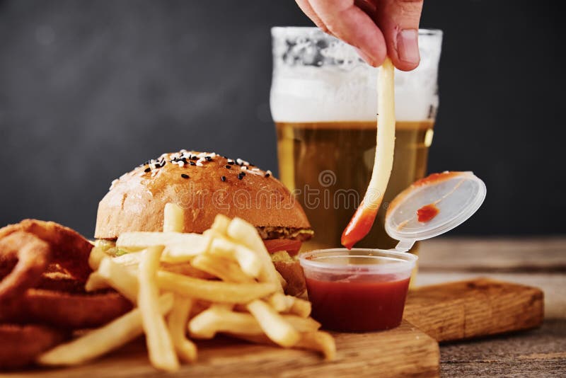 Different types of fastfood and snacks and glass of beer on the table. Unhealthy and junk food. Different types of fastfood and snacks and glass of beer on table royalty free stock image