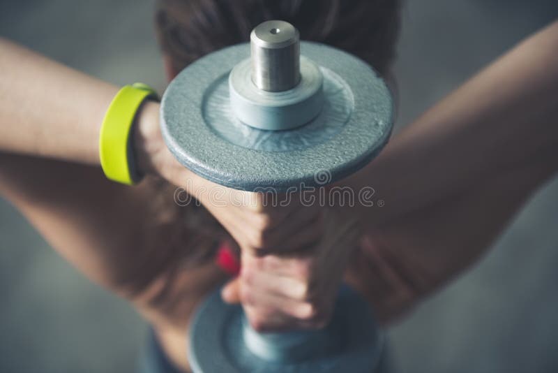 Fitness woman holding dumbbell behind head. Close up royalty free stock image