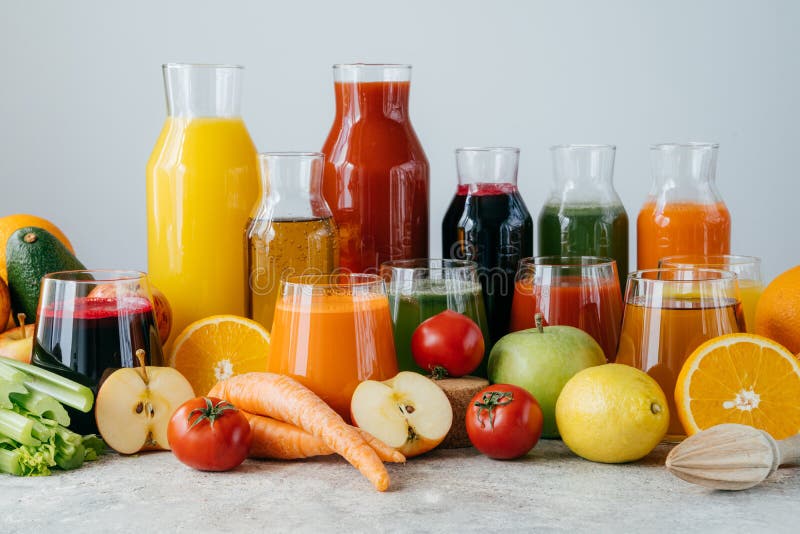 Fresh juice made of various vegetables and fruit in glass jars on grey table, isolated over white background. Freshly squeezed royalty free stock images