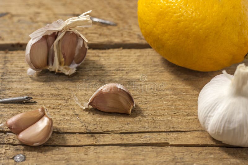 Garlic clove and lemon on a wooden background. The concept of the treatment of colds with folk remedies stock photos