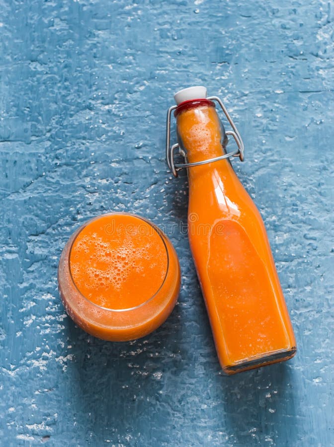Glass and takeaway bottle with vitamin mango magic smoothies on a blue background, top view.  Smoothies with ripe mango, carrot,. Orange, honey, ginger. Detox stock photo