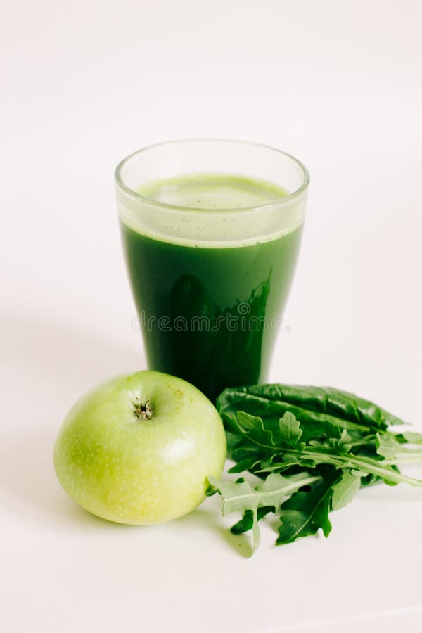 Green freshly squeezed juice from green Apple and young beet leaves on a white background stock image