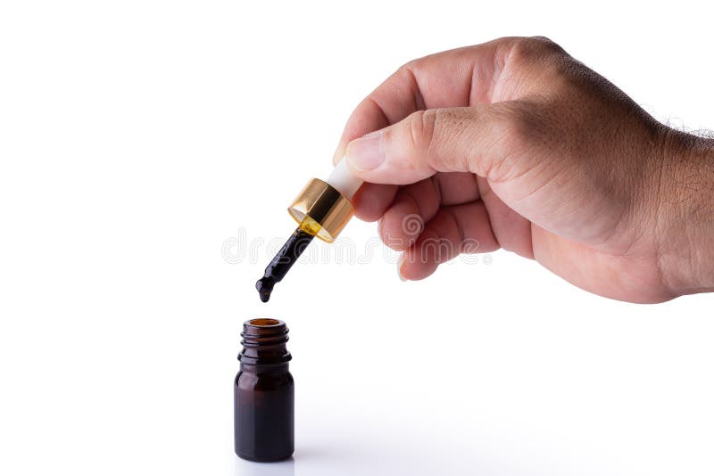 Hand holding pipette of Cannabis oil over a bottle stock images