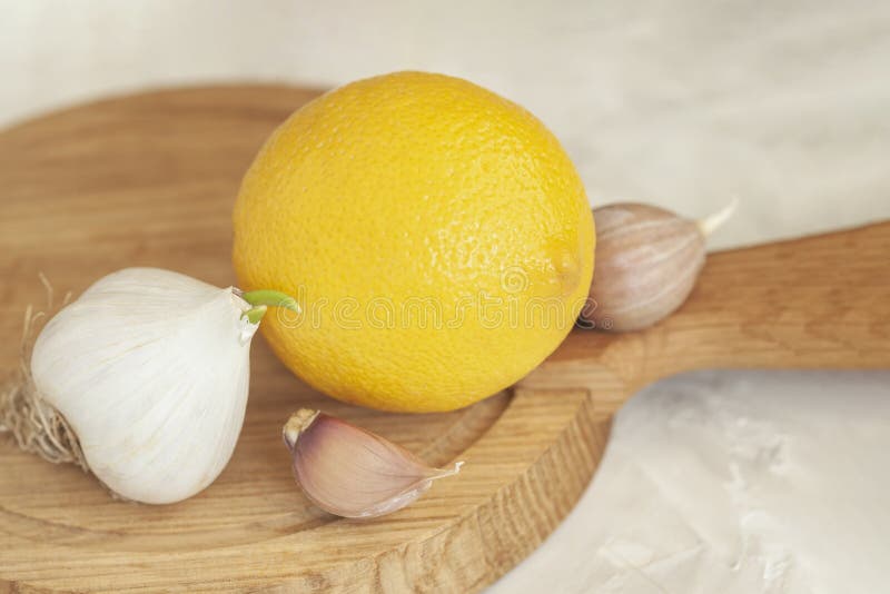Head of garlic with slices and lemon on wooden cutting board close-up, folk remedies for flu and colds, concept of stock images