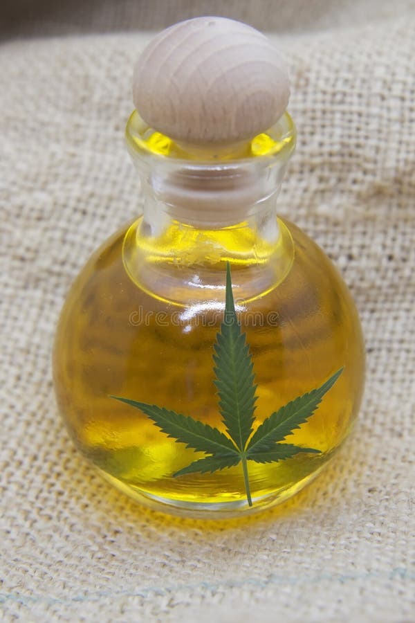 Hemp seed oil in the glass bottle with the hemp leaf on the hemp fabric royalty free stock image