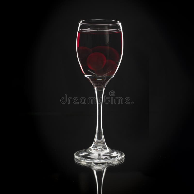 Homemade tincture of red cherry. Berry alcoholic drinks concept. Homemade red wine made from ripe cherries in wineglass on black. Background, Ukraine, close up stock images