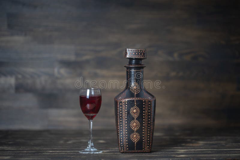 Homemade tincture of red cherry in a decorative bottles and a wineglass on wooden background, Ukraine. Close up stock photos
