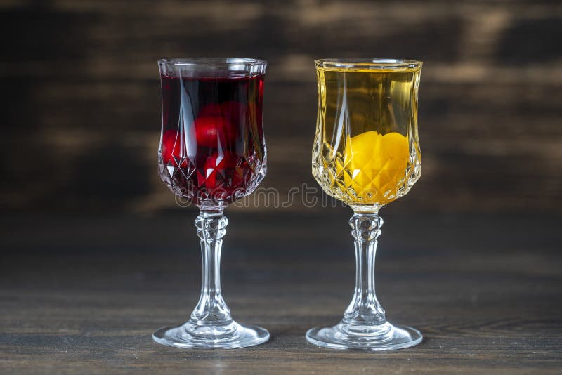 Homemade tincture of red cherry and yellow cherry plum in a wine crystal glasses on wooden background, Ukraine. Close up. Berry alcoholic drinks concept royalty free stock photos
