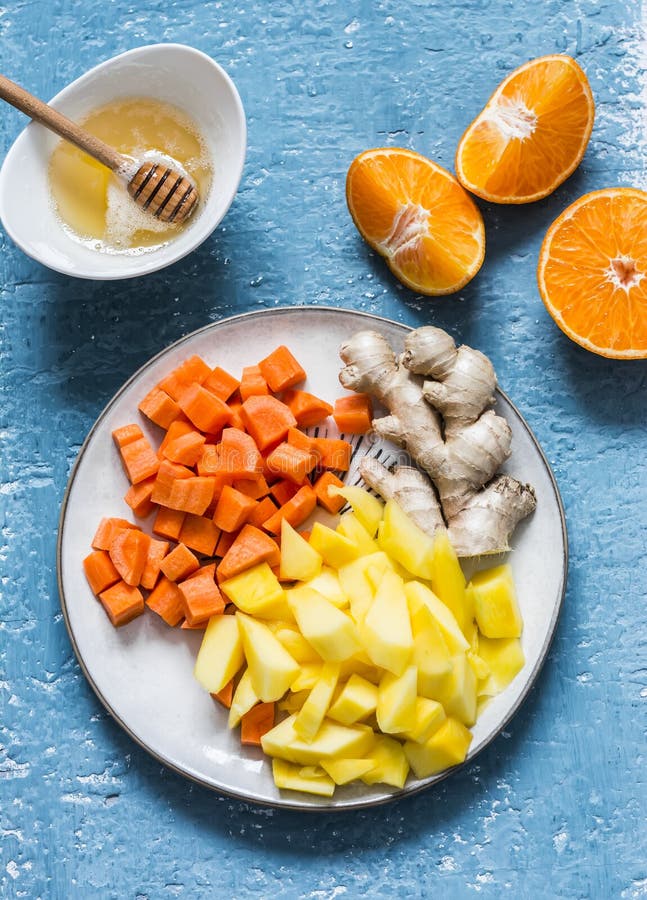 Ingredients for vitamin smoothies - fresh ripe mango, carrot, orange, honey, ginger on a blue background, top view. Detox healthy. Drink royalty free stock image