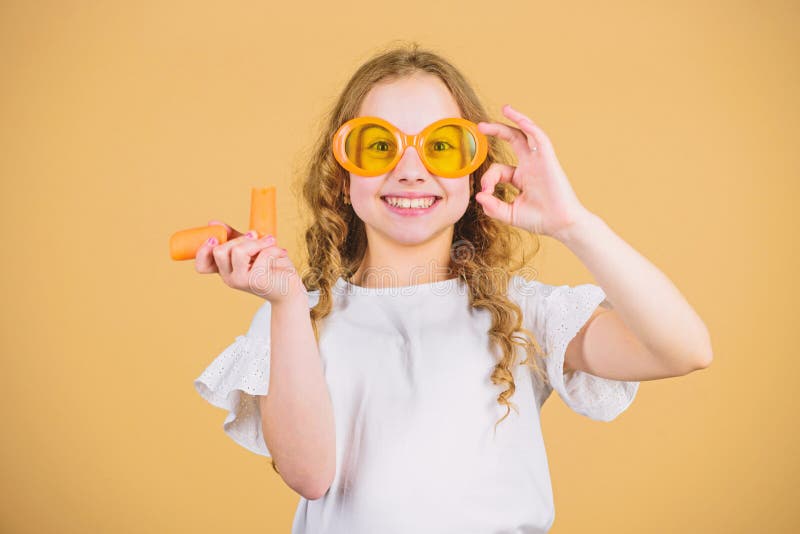 Natural vitamin source. Girl eat carrot vegetable and drink carrot juice. Vitamin nutrition. Fashion kid sunglasses. Drink refreshing vitamin juice. Health care royalty free stock image