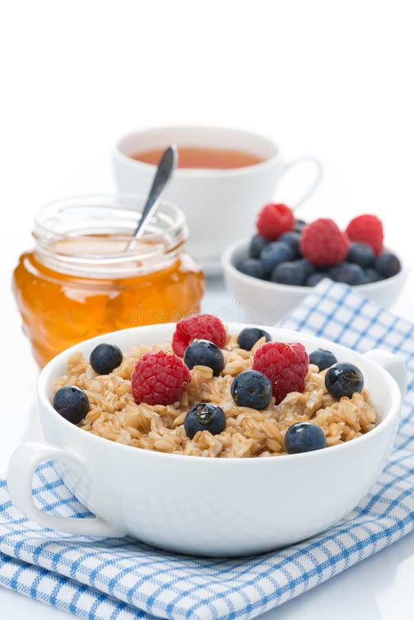 Oat porridge with fresh berries and honey, a cup of black tea stock image