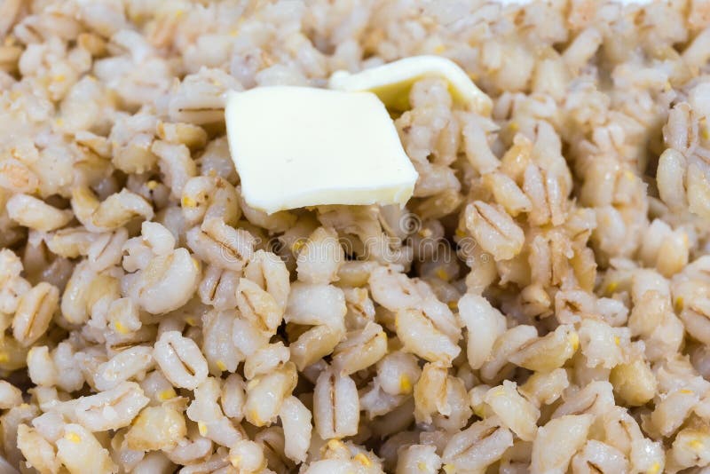 Pearl barley porridge with butter close-up, fragment, background. Pearl barley porridge with butter pieces close-up in selective focus, fragment, texture stock photography