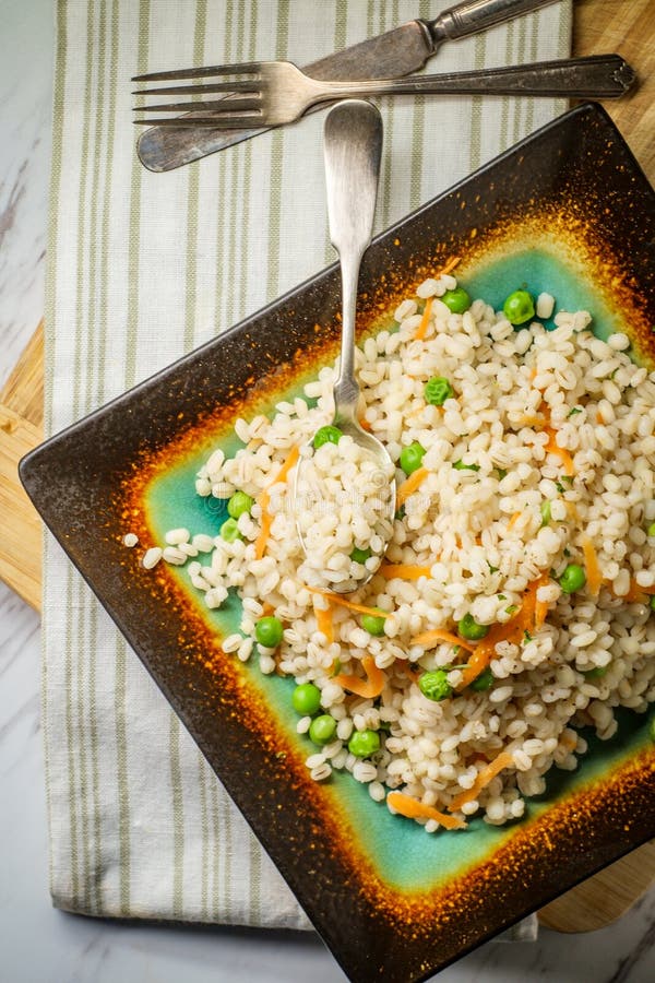 Pearled Barley Porridge. Cooked pearled barley porridge with green peas and grated carrots royalty free stock photography