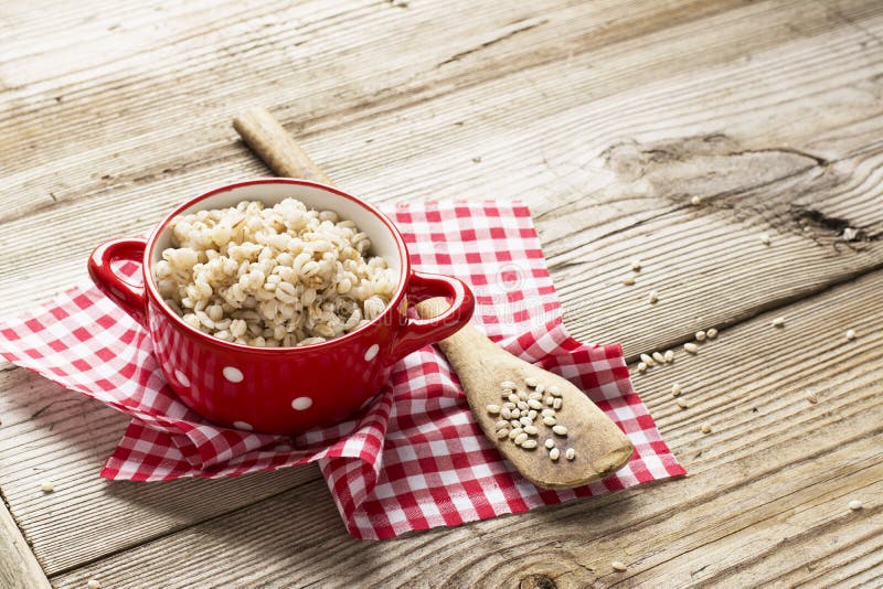 The red ceramic saucepan with white polka dots complete crumbly barley porridge royalty free stock images