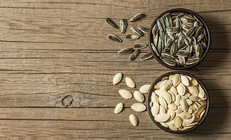Roasted sunflower seeds and pumpkin seeds in brown bowl on wooden table royalty free stock images