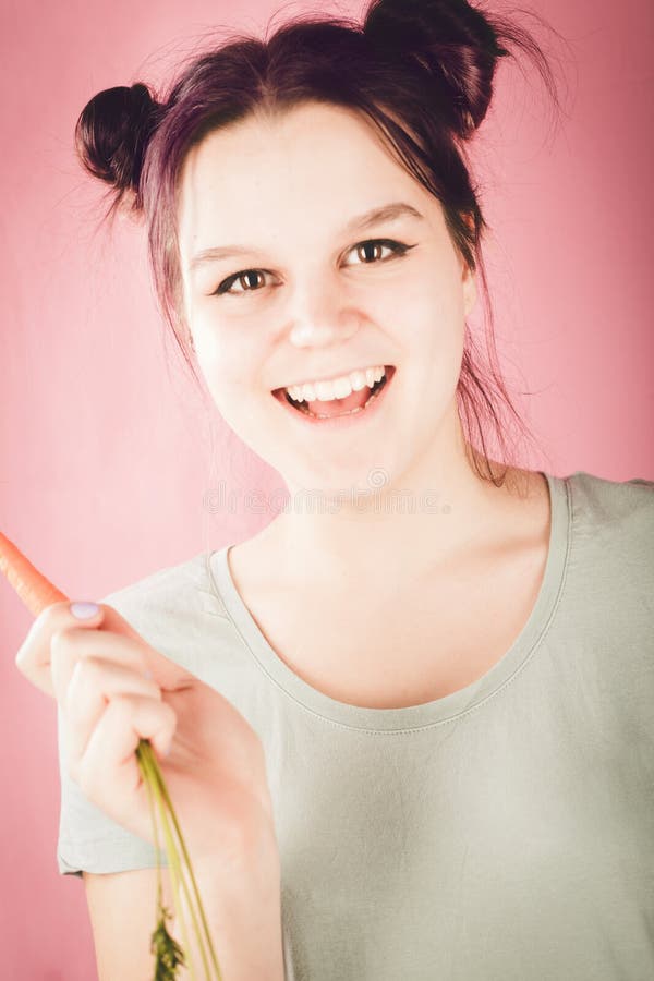Smiling young teenage girl holding vitamin-rich carrot and looking at camera. Vegetarian, diet and healthy eating conceptconcept stock photos