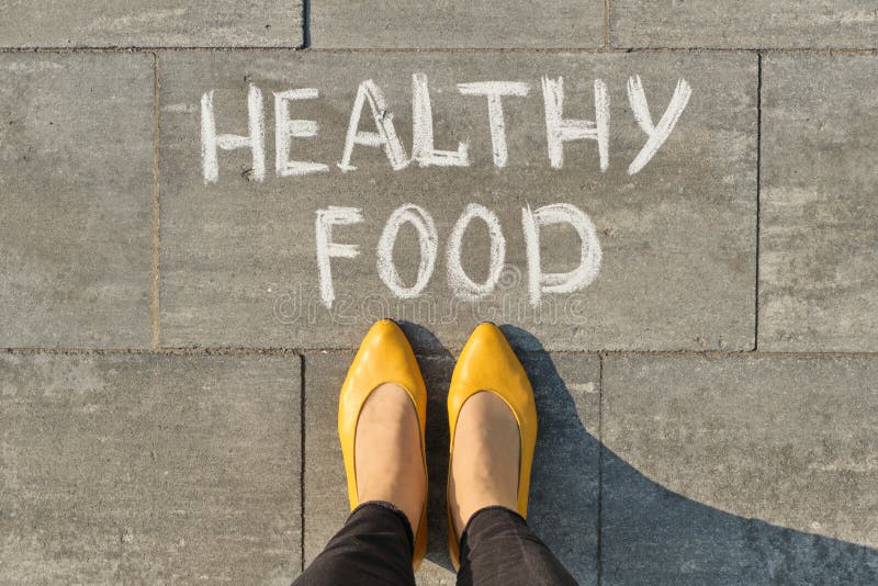 Text healthy food written on gray sidewalk with women legs, top view.  stock photography