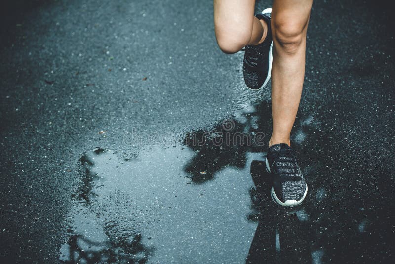 Urban city running jogging sport healthy people concept close up legs and shoes run. On wet asphalt road royalty free stock photo