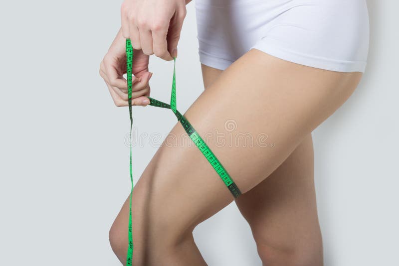 Young beautiful athletic girl measures thighs and legs measuring tape, healthy lifestyle, fitness, exercise, healthy slim body stock photos