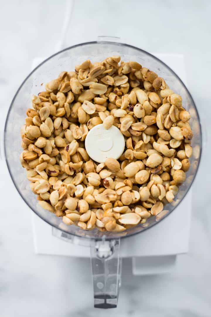 Overhead image of roasted peanuts in the food processor, ready to make Honey Roasted Peanut Butter.