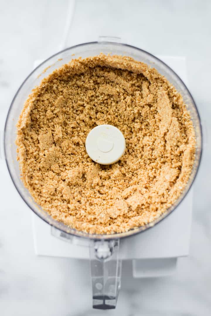 Overhead view of the food processor full of peanuts partially processed in preparation for Honey Roasted Peanut Butter.