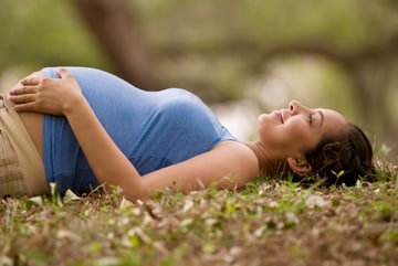 Pregnant woman lying on her back on the grass