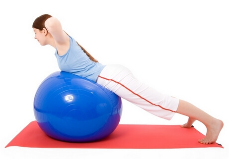 Young woman performing fitness exercises with a fitness ball