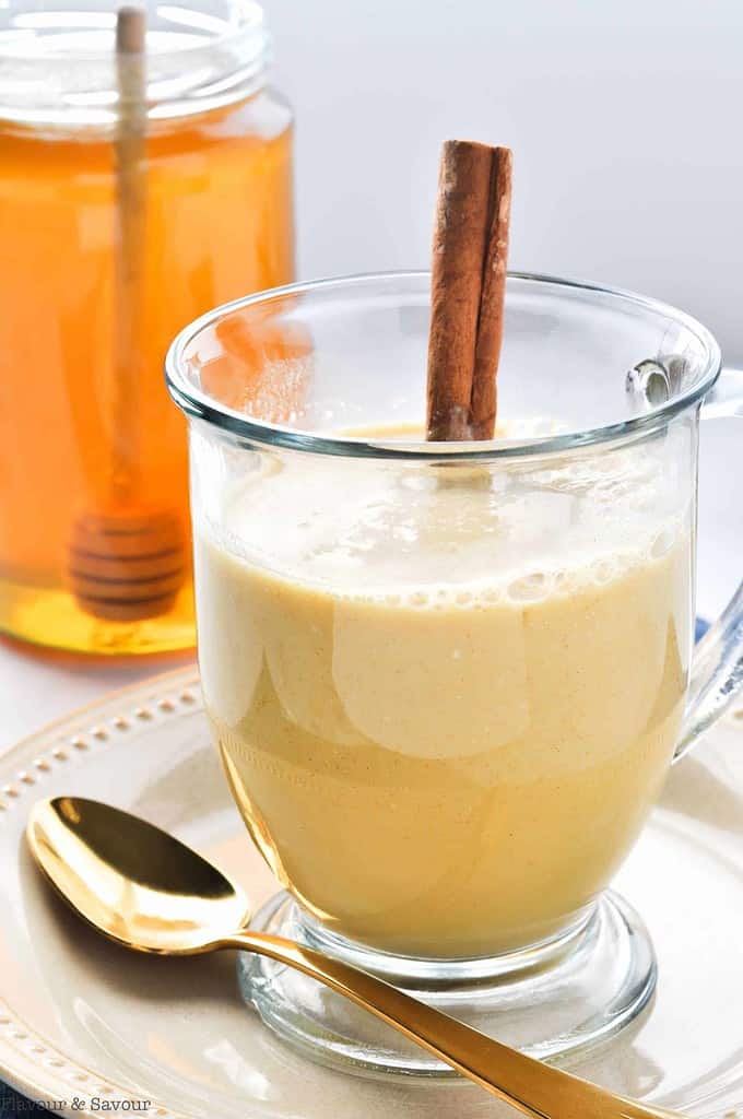 Warm Turmeric Cinnamon Milk in a glass mug with a cinnamon stick