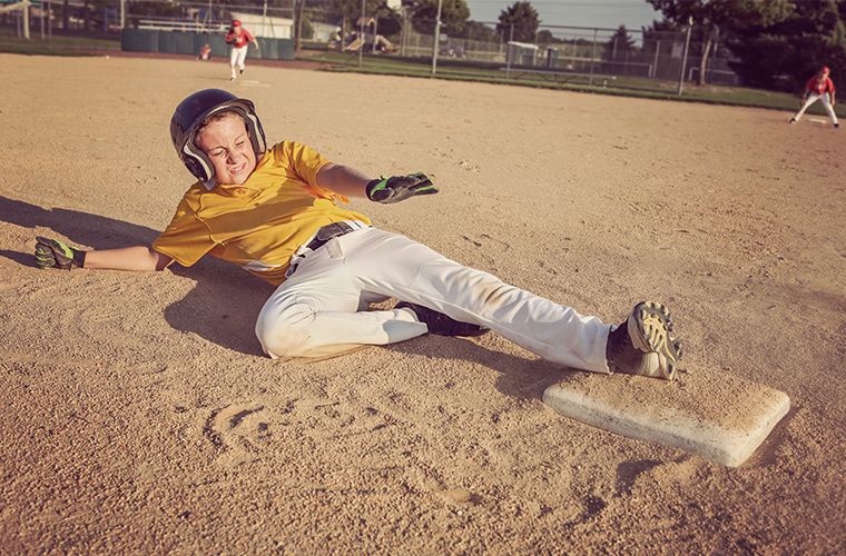 Photo of young baseball player sliding into second base.