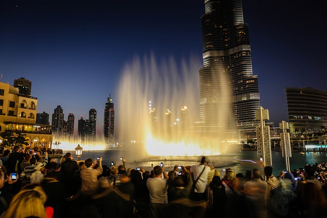 A group of people watching a fountain beneath skyscrapers in Dubai